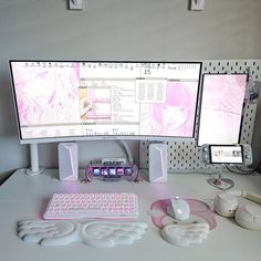 two computer monitors sitting on top of a desk next to speakers and headphones in front of them