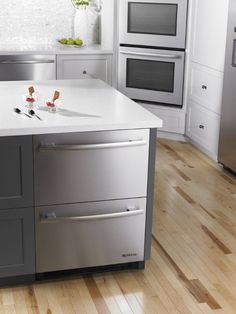 a modern kitchen with stainless steel appliances and white counter tops, along with hardwood flooring