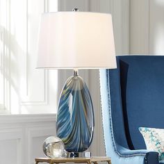 a lamp that is sitting on a table next to a blue chair with a pillow