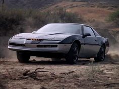 a silver car driving down a dirt road