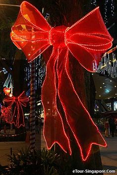 a large red bow on top of a tree in the middle of a city at night