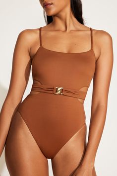 a woman wearing a brown one piece swimsuit with a gold buckle on the side