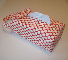 a red and white polka dot bag with tissue paper on the top, sitting on a table