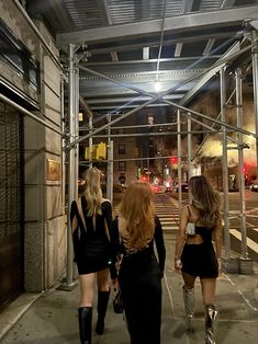 three women are walking down the sidewalk in short skirts and high heeled knee boots