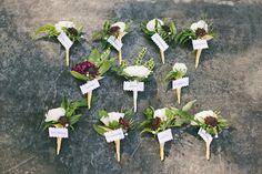 small flowers are placed on toothpicks with name tags attached to them, sitting on a cement surface