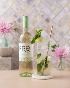 a bottle of alcohol and a glass with a drink in it on a table next to flowers