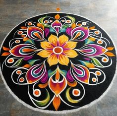 a black and white circular rug with colorful designs on the floor in front of it