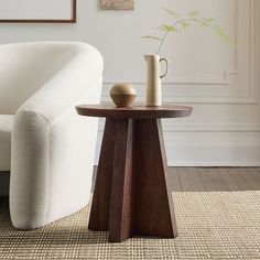 a small table with a vase on it next to a white couch in a living room