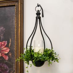 a candle is lit in a hanging potted plant next to a painting on the wall