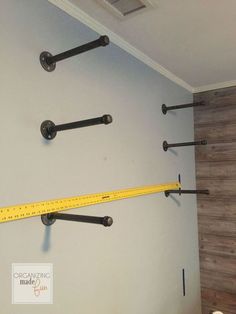 there is a measuring tape hanging on the wall next to some hooks and a ruler