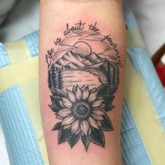 a sunflower tattoo on the arm that says life is about the mountains and trees