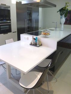 a modern kitchen with white counter tops and stainless steel appliances