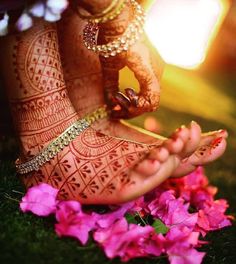 the feet and hands of a woman with henna tattoos on them, surrounded by pink flowers