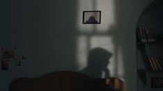 the shadow of a person's head on a wall next to a book shelf