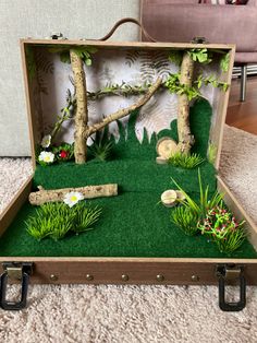 an open suitcase sitting on top of a carpeted floor covered in fake grass and trees