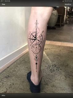 a woman's leg with a compass tattoo on it and an arrow in the middle