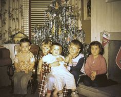 a group of children sitting in front of a christmas tree