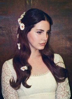 a woman with long brown hair and flowers in her hair is wearing a white dress