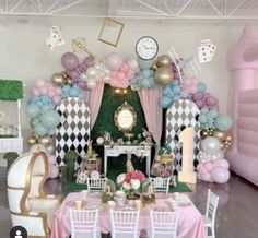 a party setup with balloons, tables and chairs in front of a checkerboard backdrop