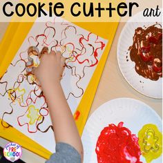 a child is painting on paper plates with cookie cutters