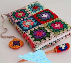 a crocheted book with a pen and yarn next to it