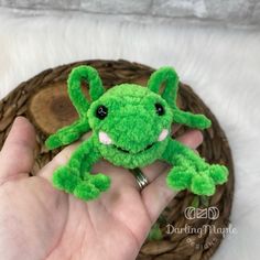 a hand holding a small green stuffed animal