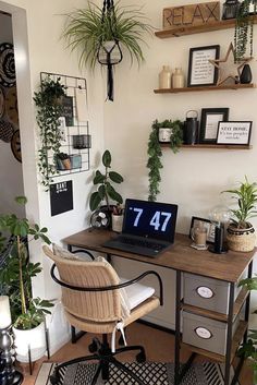 a desk with a laptop on top of it in a room filled with potted plants