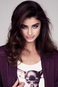 a woman with long brown hair wearing a t - shirt and cardigan jacket is posing for the camera