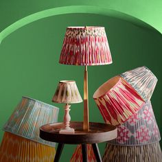 three lamps sitting on top of a wooden table next to a lamp shade in different colors