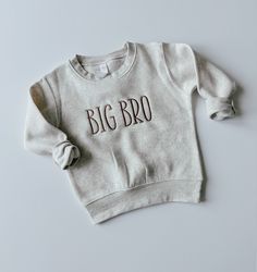 This sweet and simple embroidered big bro shirt is perfect for any little boy whether they are already a big brother or about to become one.  This cozy sibling sweatshirt features a brown text on an oatmeal sweatshirt and is the perfect combination of comfort, simplicity and cuteness! If you are interested in other colors and/or words, send me a message and we can find something that meets your needs!   Details: This sweatshirt is a 60/40 cotton/polyester blend Thread is polyester Embroidery Wash and Care: -Always wash your garment before use -Wash inside out with mild detergent -Wash on cold, gentle cycle -Do not use chlorine bleach -Lay or hang to dry Items will ship USPS First Class.  Please contact us with any questions! Brown Sweatshirt, Big Brother Shirt, Brother Shirts, Big Brother, Embroidered Shirt, Kids Tops, Sweat Shirt, Kids Outfits, Tops & Tees