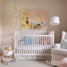 a baby's room with a crib, rocking chair and painting on the wall