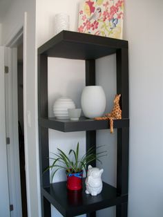 a shelf with some vases on top of it and a small potted plant next to it