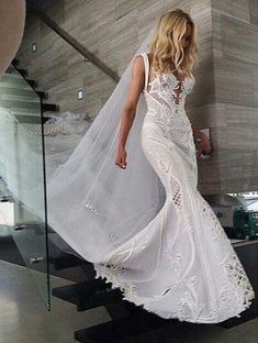 a woman in a white wedding dress is walking up some stairs with a veil over her head