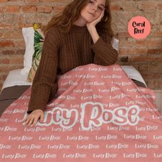 a woman sitting on top of a bed with a pink blanket over her head and the words rosy rose written across it