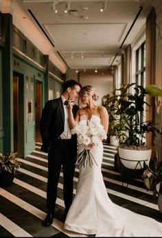 a bride and groom standing together in the hallway