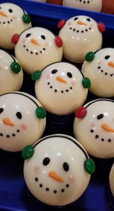 many snowmen with green and red noses are in a blue tray on the table