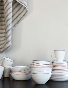 a stack of white bowls sitting on top of a wooden table next to a towel