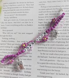 a book with some beads and charms on top of an open book pages that says love