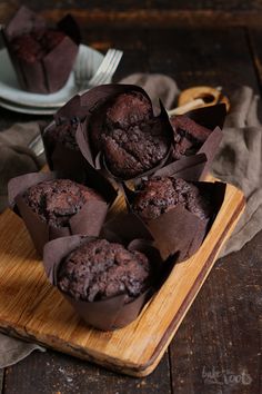 some chocolate muffins are on a wooden tray