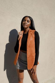 Suede Vest: A suede open vest featuring a longline silhouette, notched lapels, and sleeveless.  
Checkered Mini Skirt: A woven skirt featuring an allover plaid pattern, partially elasticized waist, and front inverted pleats. Suede Vest, Sleeveless Vest, Long A Line, Plaid Pattern, Mini Skirts