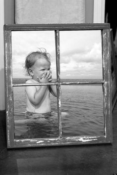 a baby in the water looking through a window