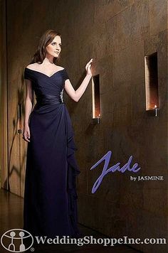 a woman in a black dress is standing by a wall with candles on the side