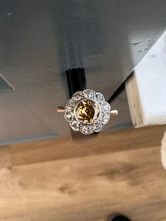 a yellow and white diamond ring sitting on top of a wooden table