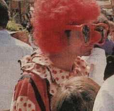 a person with red hair and glasses holding a dog