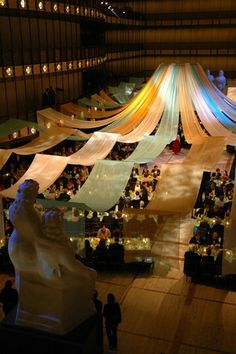 an overhead view of people sitting at tables in a large room with white draping on the ceiling