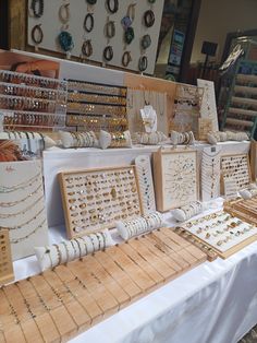 a table topped with lots of jewelry and bracelets next to wall mounted pictures on wooden boards