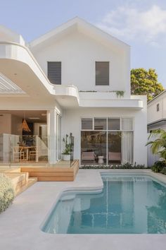 a large white house with a pool in the front yard and an outdoor dining area