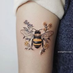 a woman's arm with a tattoo of a bee and flowers on the side