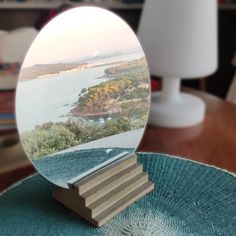 a mirror sitting on top of a wooden table next to a lamp and a book