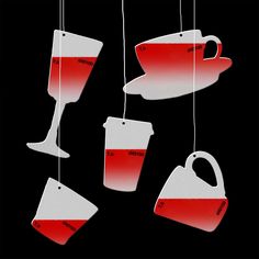 red and white coffee cups hanging from strings with tags attached to the strings, on a black background